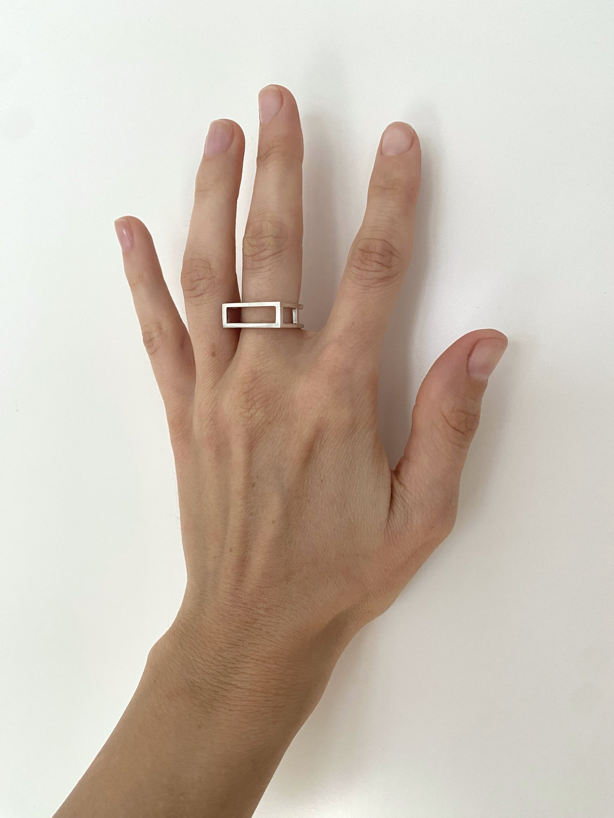 Hand wearing a silver ring on a white background
