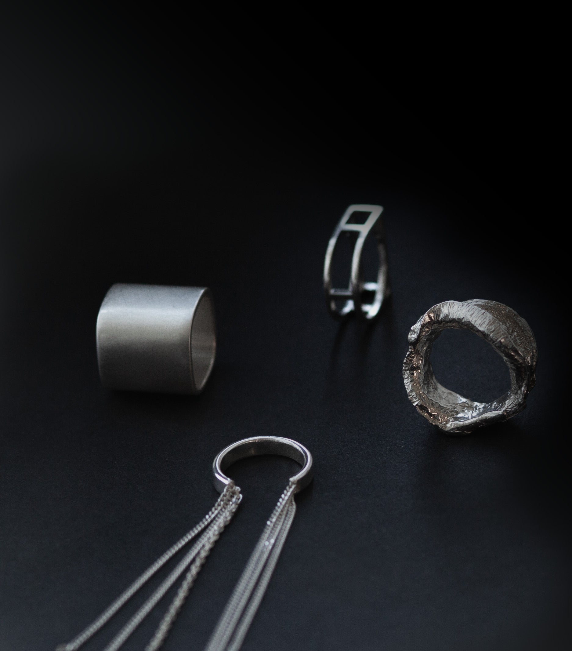 Four pieces of silver jewelry on a black background