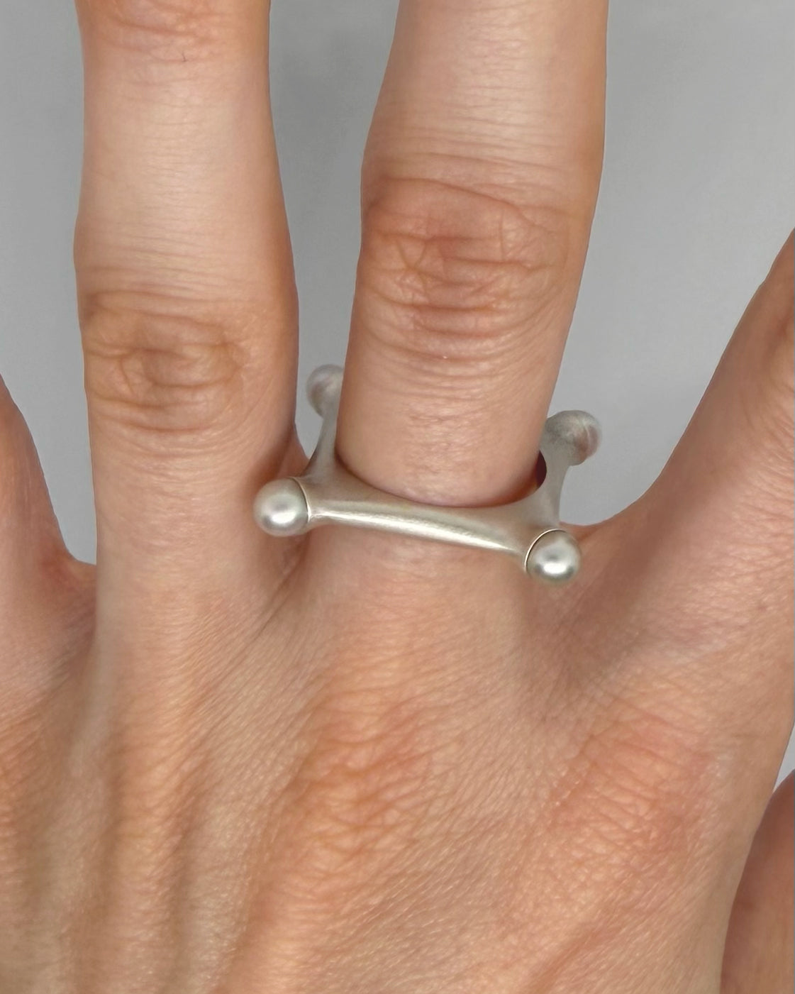 Silver ring on a person's finger against a neutral background