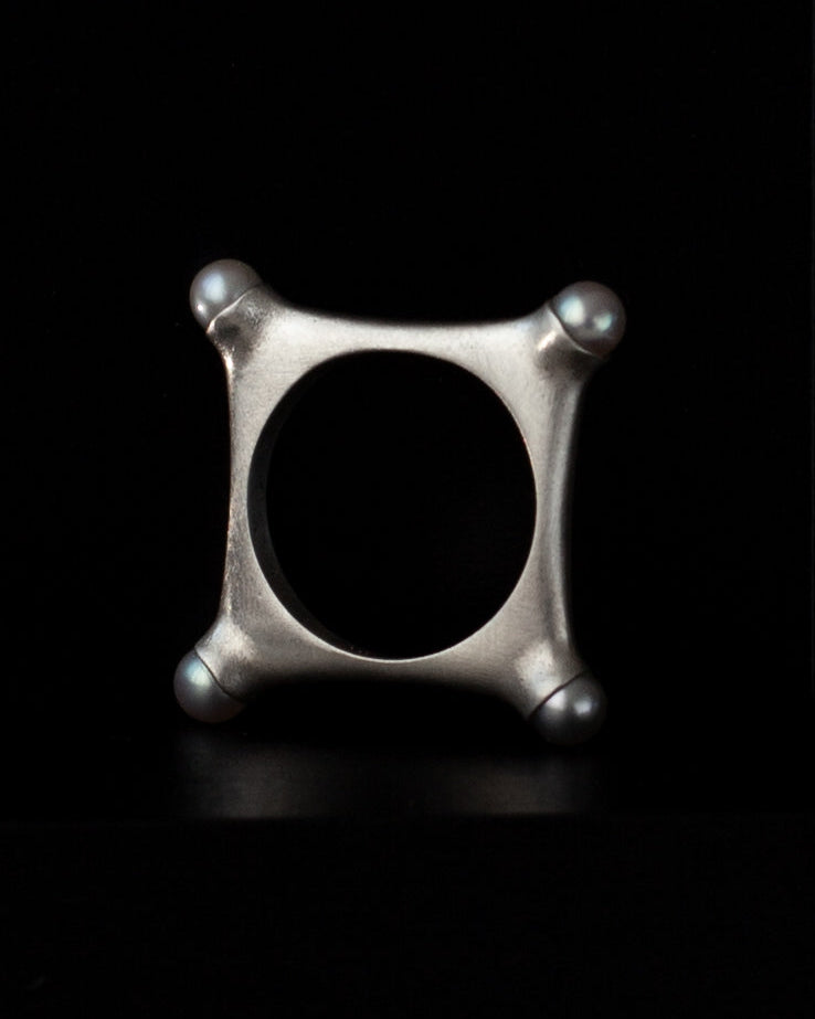 Argentium silver geometric ring with 4 pearls in corners on a black background