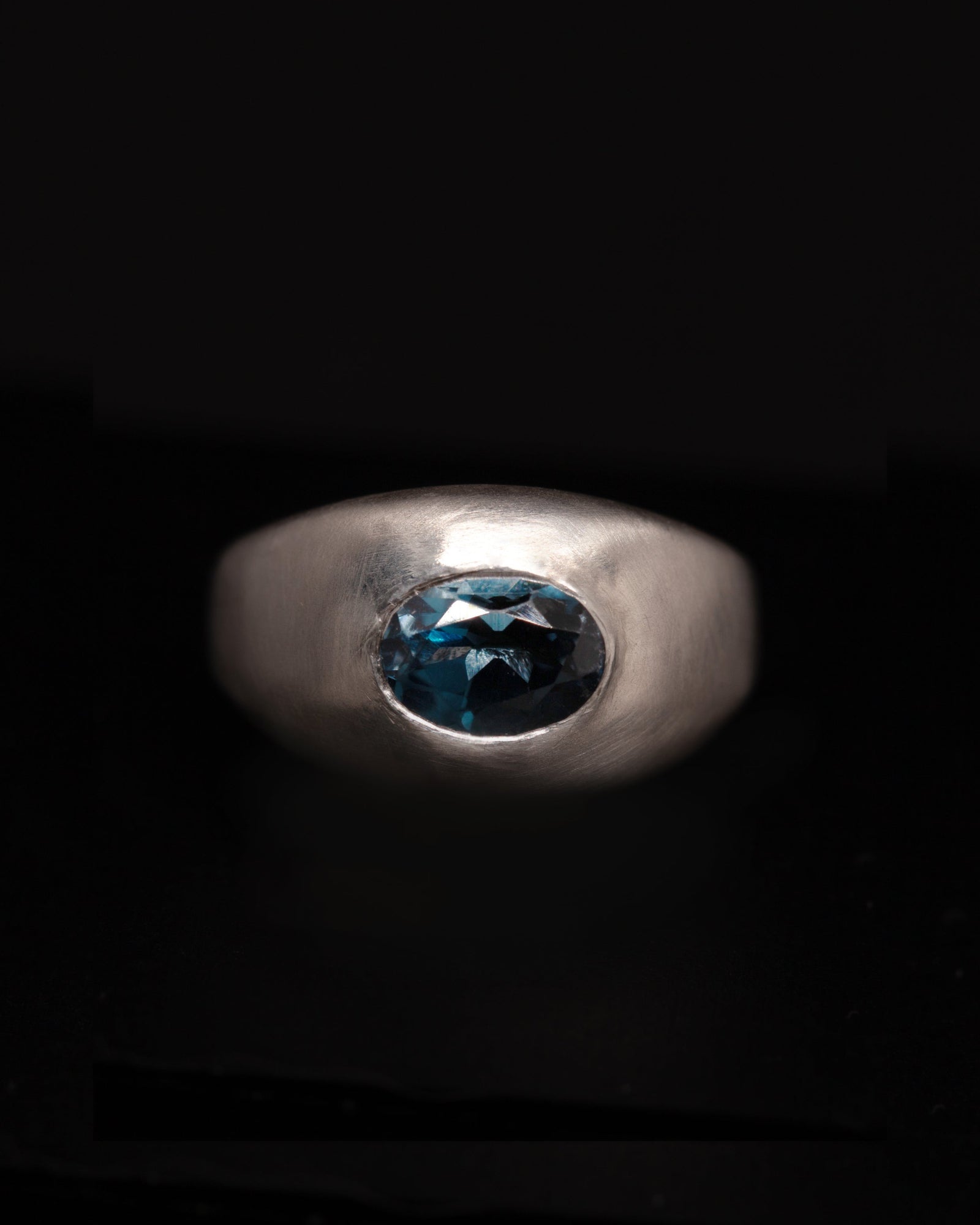 Silver ring with London blue topaz oval gemstone on a black background