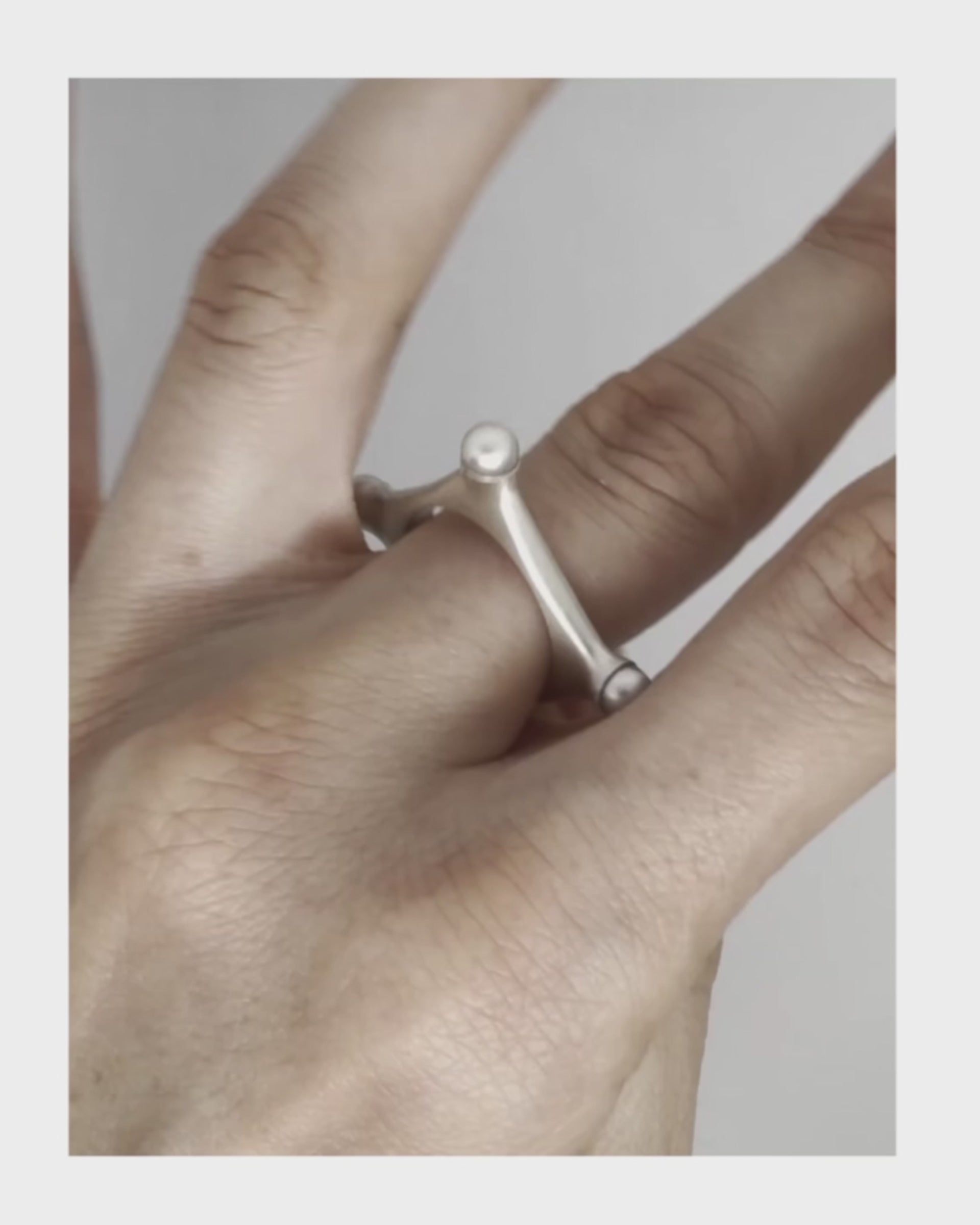 Closeup of a hand rotating Argentium silver ring with fresh water pearls