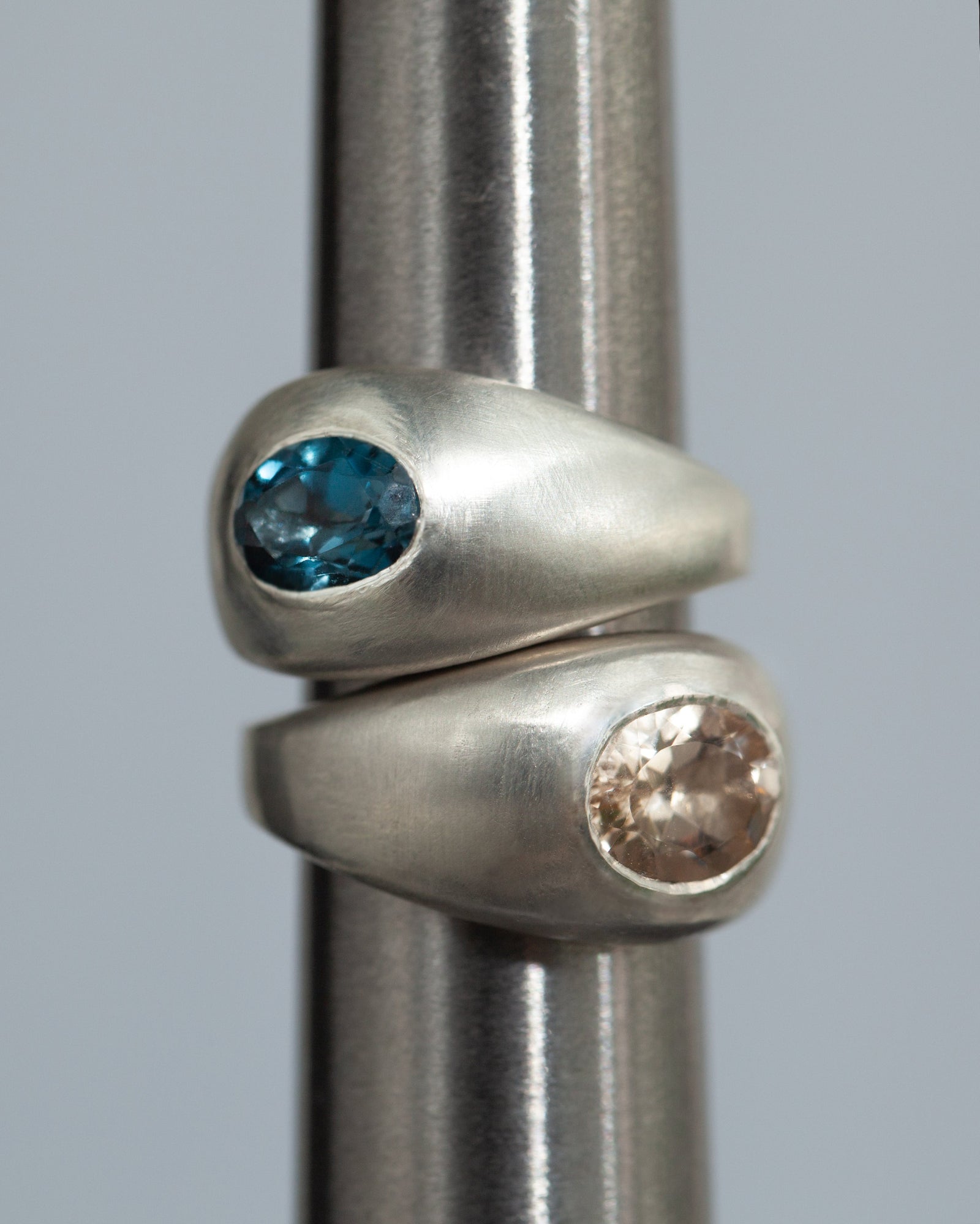 Two silver rings with gemstones on a gray background